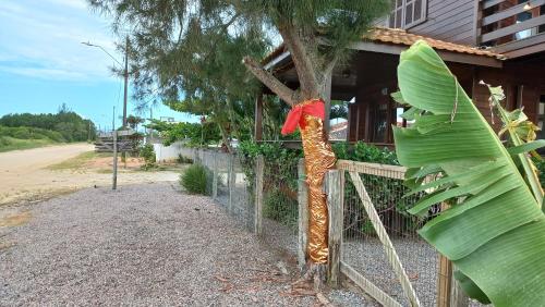 a fence with a tree in front of a house at La Tatuira, Cabana Amarela in Pinheira
