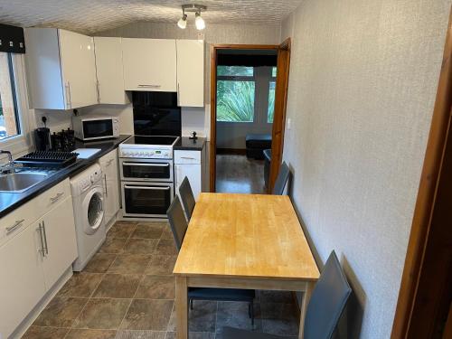 a kitchen with a wooden table and a counter top at Snowdonia cabin in Caernarfon