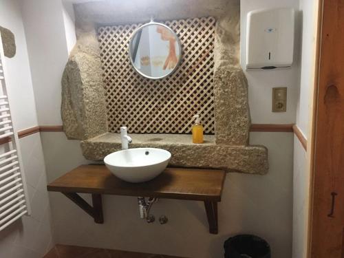 ein Badezimmer mit einem weißen Waschbecken und einem Spiegel in der Unterkunft O Lagar de Jesús in Padrón