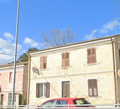 un'auto rossa parcheggiata di fronte a un edificio di Casa Adelaide vicino al mare,uscita Ancona Sud ad Ancona