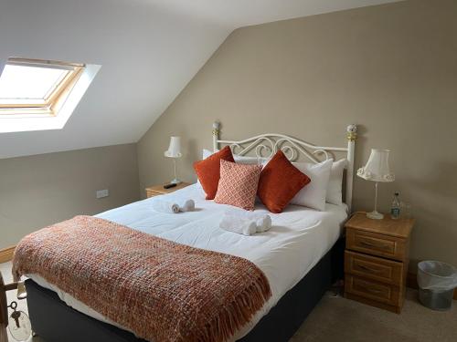 a bedroom with a large bed with red pillows at The Copper Still Bar in Dromod