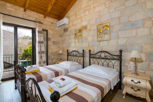 two beds in a bedroom with a stone wall at Villa Constancia in Stalos