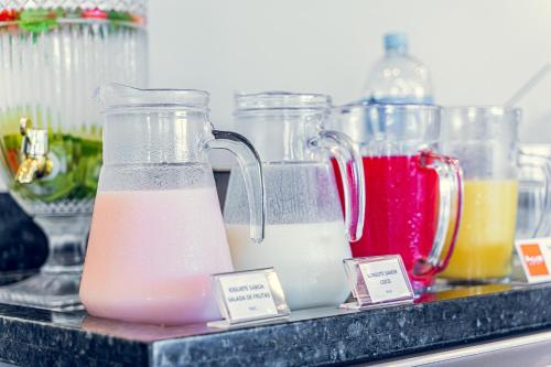 a shelf with four jars of different colored drinks at HUS HOTEL Dourados in Dourados