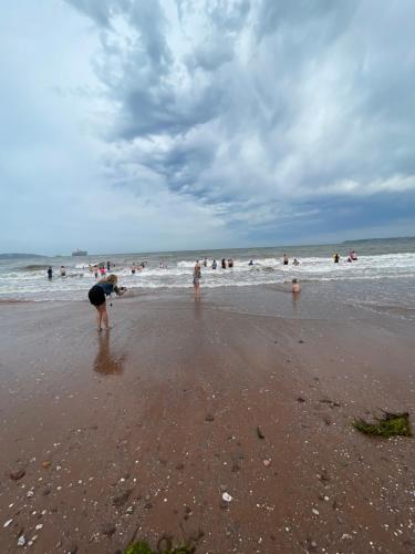 a person standing on a beach with people in the water at B23 in Goodrington
