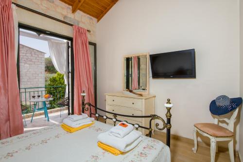 a bedroom with a bed with a television and a balcony at Villa Constancia in Stalos