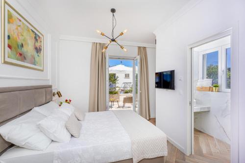 a white bedroom with a bed and a balcony at Rooms D&L, FREE Parking on-site in Dubrovnik