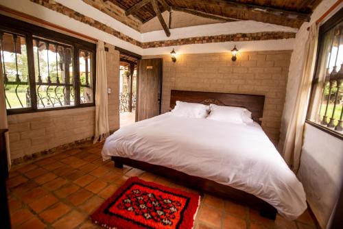 a bedroom with a large bed in a room with windows at Hospedaje Villa Eucalyptus in Nobsa