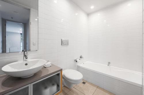 uma casa de banho branca com um lavatório, uma banheira e um WC. em Lakeside Apartment Waimahana 1 em Taupo
