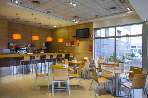 a restaurant with tables and chairs and a bar at Hotel La Boroña in Gijón