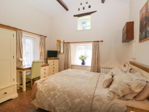 a bedroom with a bed and a desk and windows at Topiary Cottage in Staveley