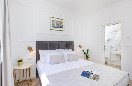 a white bedroom with a large bed with a book on it at Rooms D&L, FREE Parking on-site in Dubrovnik