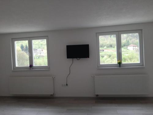 a white room with three windows and a flat screen tv at Apartman Dujmović in Visoko