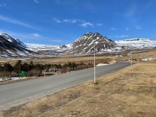 a road with a snow covered mountain in the background at Dúfan Apartments in Bolungarvík