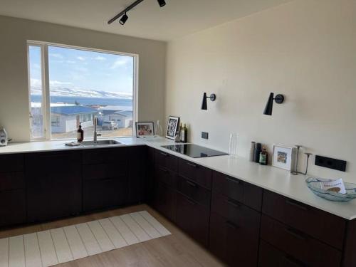 a kitchen with a sink and a large window at Dúfan Apartments in Bolungarvík
