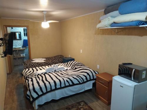 Cette chambre dispose d'un lit à motifs zébrés et d'une télévision. dans l'établissement V do Lago Negro, à Gramado