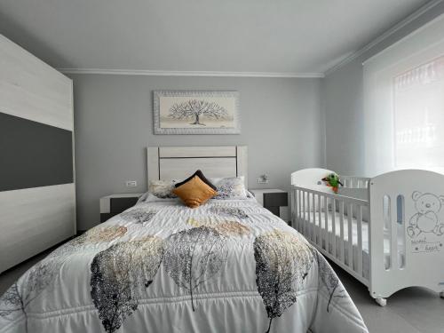 sypialnia z białym łóżkiem i łóżeczkiem dziecięcym w obiekcie Apartamentos María de Lucía-Piso 2º w mieście Arou