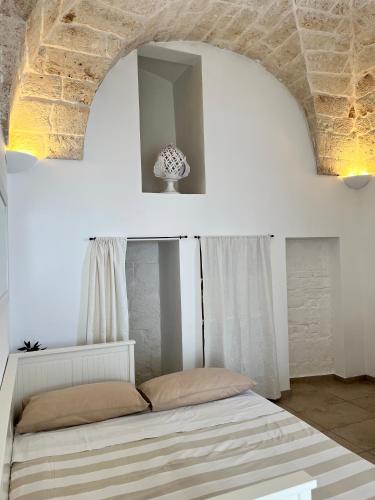 une chambre avec un lit dans une pièce blanche dans l'établissement Angoletto Bianco, à Ostuni