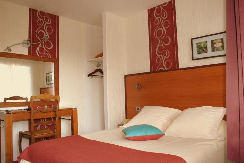 a bedroom with a bed with a wooden headboard and a table at Hotel Capricorne in Vendôme