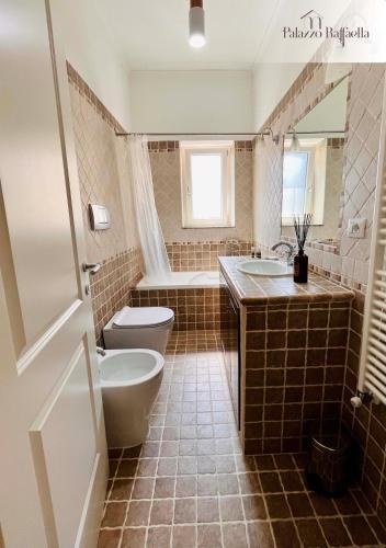 a bathroom with two sinks and a toilet and a tub at Appartamento Palazzo Raffaella in Castel SantʼElia