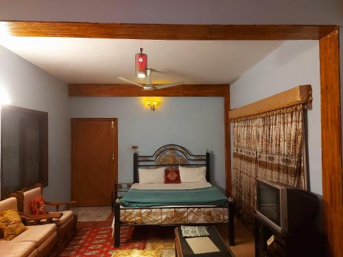 a bedroom with a bed and a couch and a tv at Bhurban valley guest house in Murree