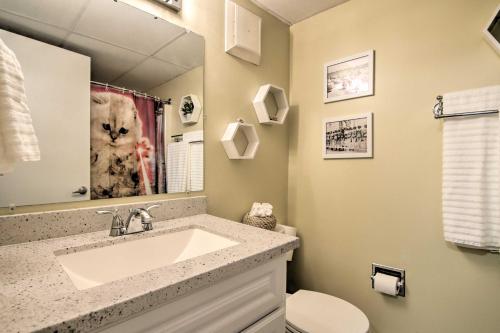 a bathroom with a sink and a cat picture in the mirror at Condo Retreat with Balcony on Ocean City Beach! in Ocean City