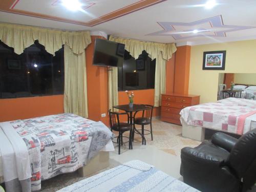 a bedroom with two beds and a table with a chair at Gran Hostal Los Pinos in Cajamarca