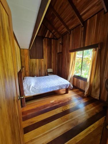 1 dormitorio con 1 cama en una habitación de madera en Casa Numú en Cahuita