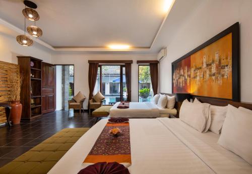 una camera d'albergo con due letti e un divano di Ubud Raya Boutique Hotel ad Ubud