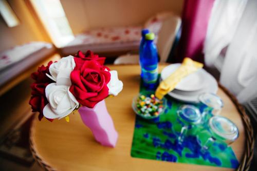a table with a flower and a bottle on it at Tanie Noclegi 2 in Kielce