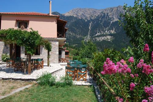 a house with a table and chairs and flowers at Dryades Guesthouse in Áno Khóra