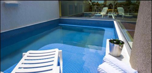 a swimming pool with a white chair and a bucket at Premium Flat Praia Calma - PontaNegra in Natal
