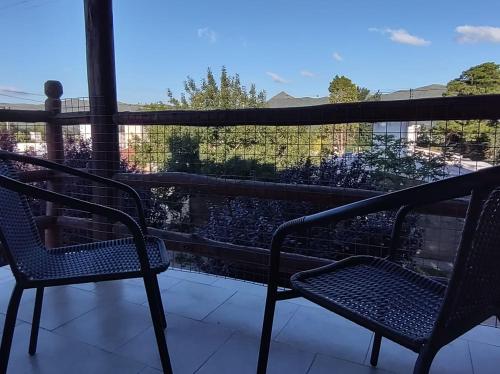 two chairs on a balcony with a view of a river at Cabaña Céntrica con Balcón Vista a las Sierras in Cosquín