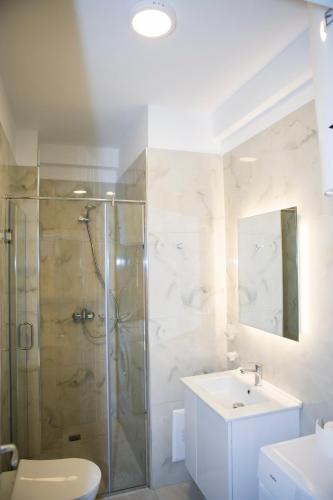a bathroom with a shower and a toilet and a sink at Soluna Apartments in Shëngjin