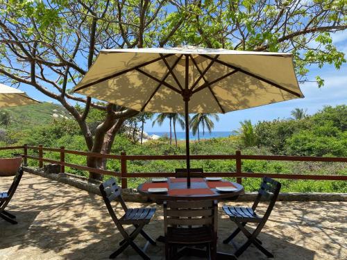 a table and chairs with an umbrella on a patio at Ecohabs Tequendama - Parque Tayrona in El Zaino
