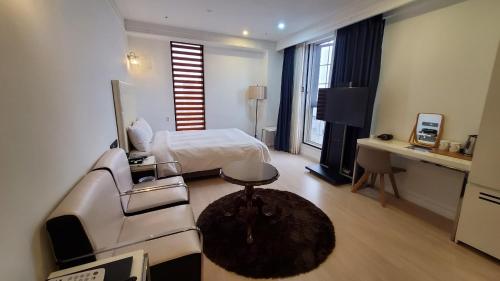a hotel room with a bed and a couch at Urban Island Hotel Jeju in Jeju