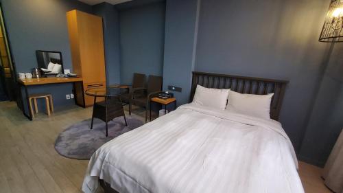 a bedroom with a large white bed and a desk at Urban Island Hotel Jeju in Jeju