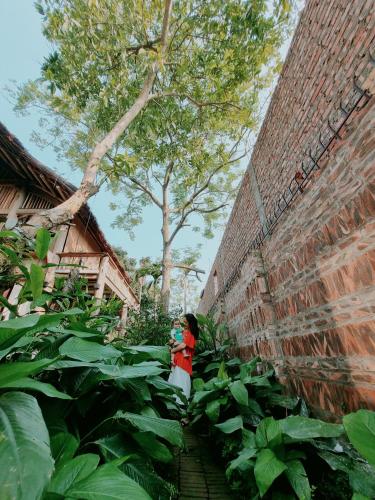 a woman is standing next to a brick wall at Mô he in Sơn Tây