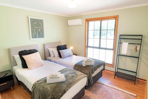 a room with two beds and a window at Hideaway@Hepburn in Hepburn Springs