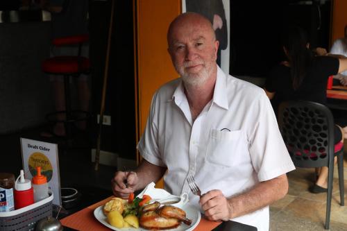 a man in an apron holding a plate of food at Hideaway Guest House And Bar in Pattaya Central