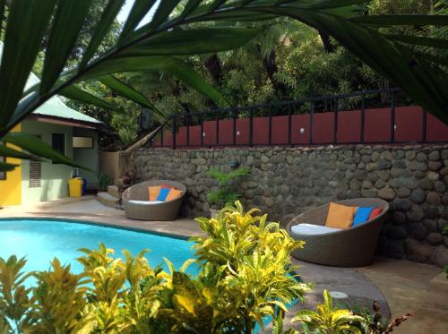 una piscina con tumbonas y una pared de piedra en Tamarindo Village Hotel, en Tamarindo