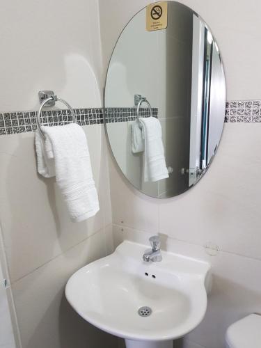 a white bathroom with a sink and a mirror at Jazmin's Apartment in Oranjestad