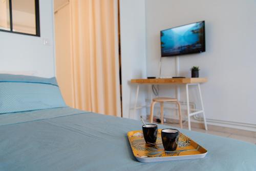 uma bandeja com duas chávenas em cima de uma cama em Studio Cosy Cahors- proche Gare et Centre-Ville em Cahors