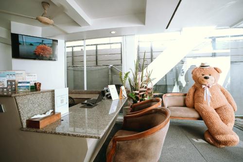 a large brown teddy bear sitting in an office at The Front Hotel and Apartments in Patong Beach