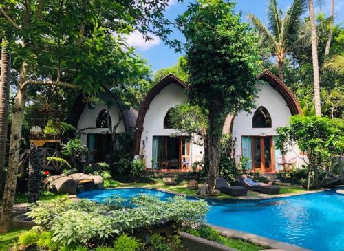a house with a swimming pool in front of it at Green Bird Villa - CHSE Certified in Ubud