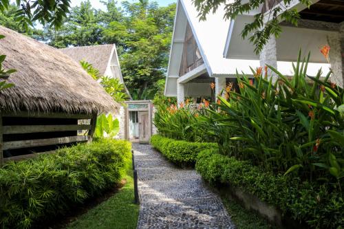 a path leading to a house with a thatch roof at Chanteak Bali in Jimbaran