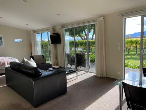 a living room with a black couch and a glass table at Walnut Block Cottages in Blenheim