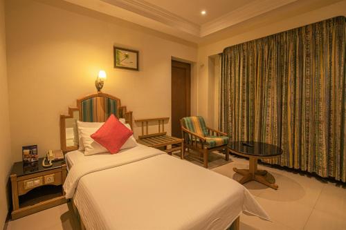 哥印拜陀的住宿－CAG普萊德酒店，卧室配有1张床、1张桌子和1把椅子