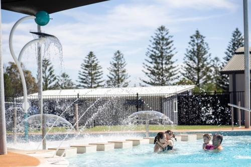 a group of children playing in a pool with a fountain at Surf Beach Holiday Park in Kiama