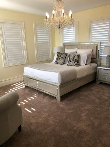 a bedroom with a large bed with a chandelier at Beach Escape Studio Walk To The Beach in Rosebud