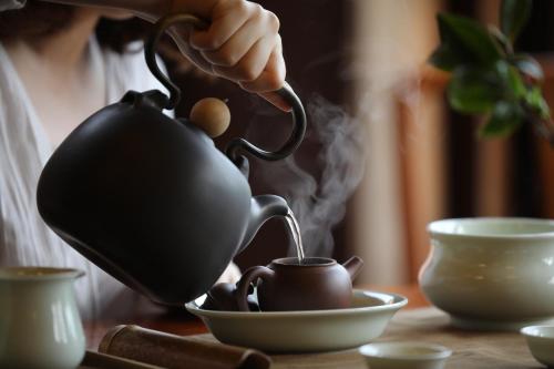 a woman is pouring tea into a tea pot at The One Nanyuan in Xinpu